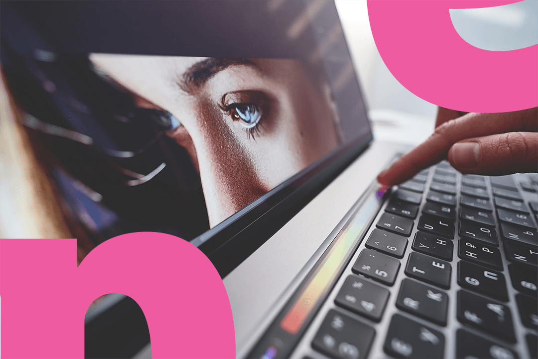  A computer screen with the picture of the person with the blue eyes. The finger is pressing a button on the keybord.